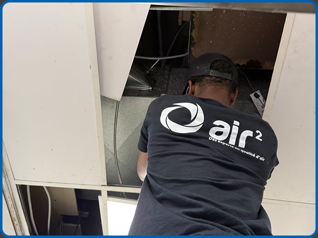 Technicien Air 2 montrant les photos avant-après au client devant l'unité de ventilation